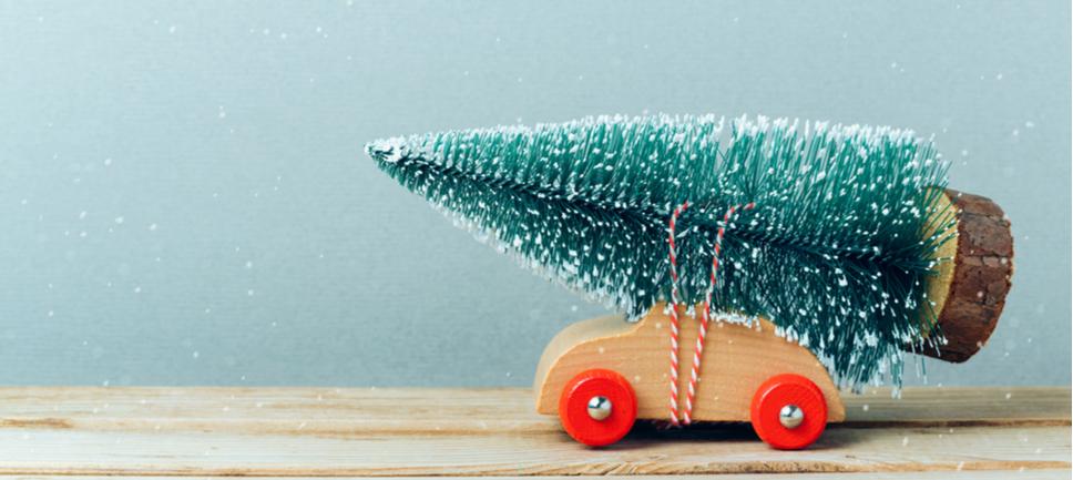 Ein Spielzeugauto aus Holz mit einem Kunstweihnachtsbaum auf dem Dach