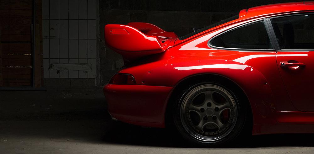 seitliche Heckansicht eines glänzenden roten Sportwagens mit Spoiler