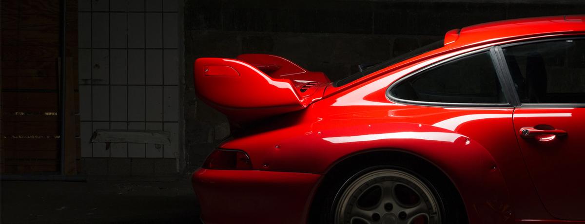 seitliche Heckansicht eines glänzenden roten Sportwagens mit Spoiler